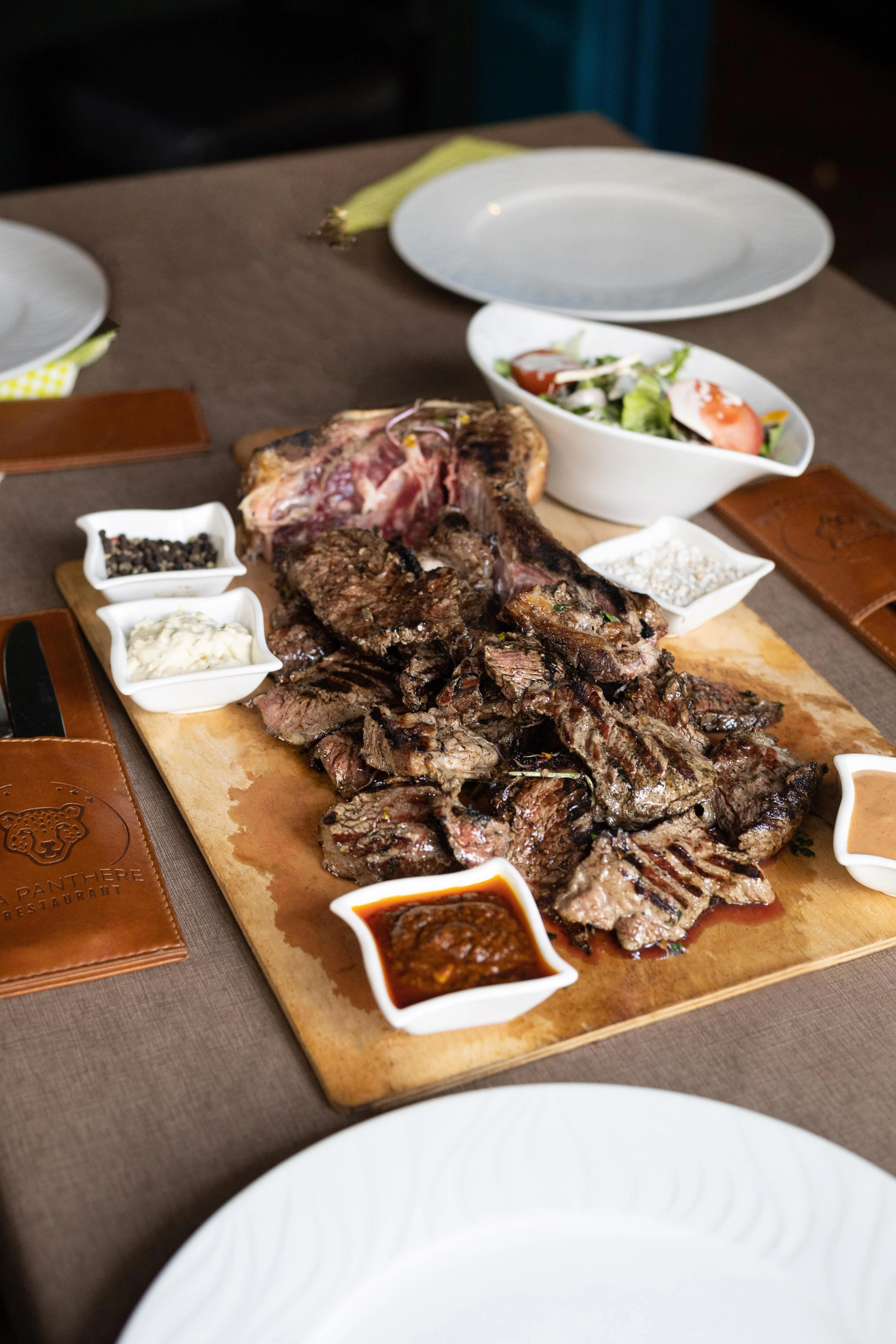 Côte de bœuf grillée tranchée sur planche, sauces maison
